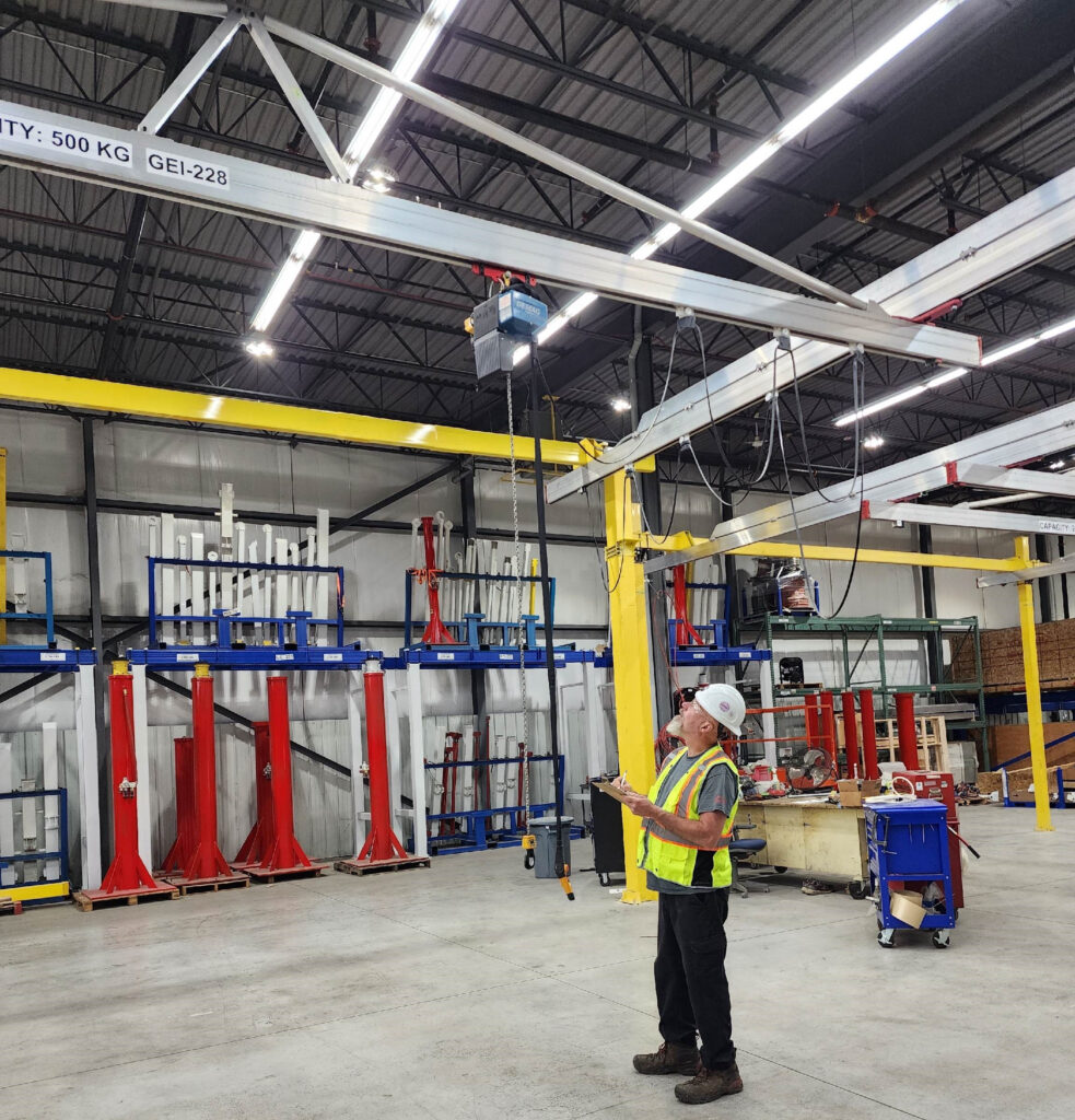 An engineer inspecting a crane in a manufacturing facility.